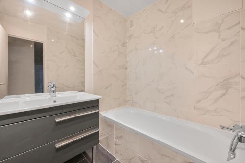 La salle de bains est pourvue d'une baignoire, d'un lavabo et d'une baignoire. dans l'établissement L’escapade Parisienne - Beau 2 pièces - Proche Paris- Netflix, à Choisy-le-Roi