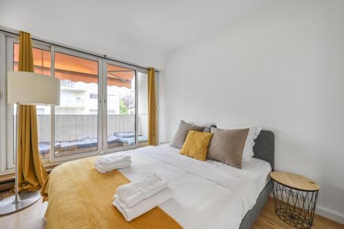 - un lit blanc avec serviettes dans une chambre avec fenêtre dans l'établissement L’escapade Parisienne - Beau 2 pièces - Proche Paris- Netflix, à Choisy-le-Roi