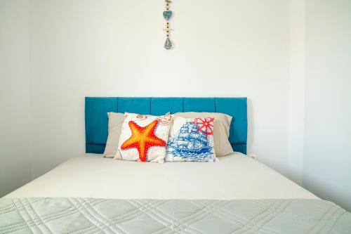 een bed met een blauw hoofdeinde en kussens erop bij Gabi's Seabreeze Nest in Nea Kalikratia