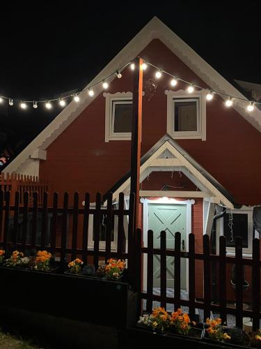 a red house with a fence and lights on it at Wioska w Sowich Sokolec in Sokolec