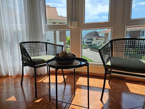 two chairs and a table in front of a window at Apto en la playa Santoña C05A02 in Santoña