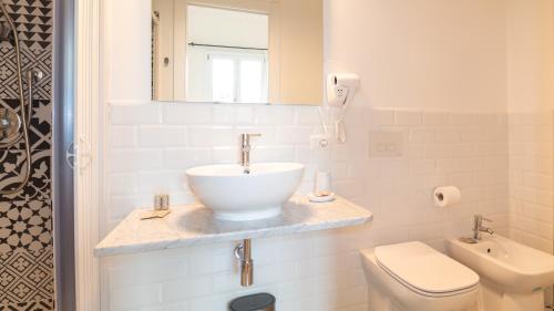 a white bathroom with a sink and a toilet at Ceramic Rooms in Oristano