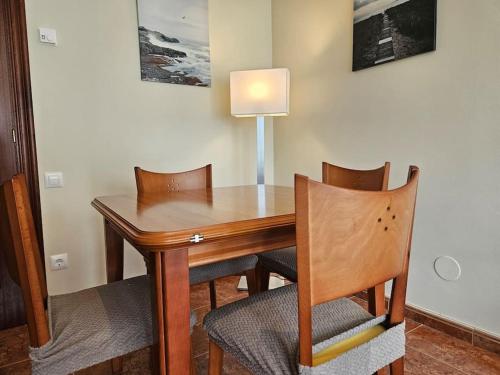 a wooden table with two chairs and a lamp at Apto en la playa Santoña C05A02 in Santoña