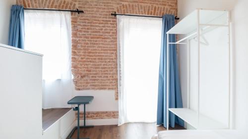 a room with a brick wall and two windows at Ceramic Rooms in Oristano