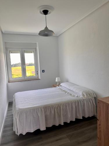 a white bedroom with a bed and a window at Miguelón in Bañugues