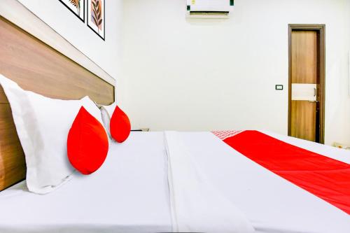 Super OYO Collection O Hotel White Prime في فاغوارا: غرفة نوم بسرير ابيض ومخدات حمراء