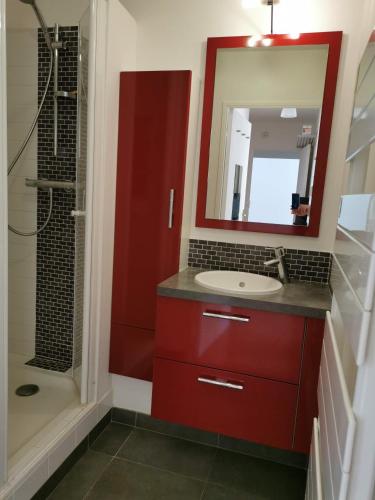 La salle de bains est pourvue d'une armoire rouge et d'un lavabo. dans l'établissement Appartement de 60m2 dans une belle résidence calme, à Neuilly-sur-Marne