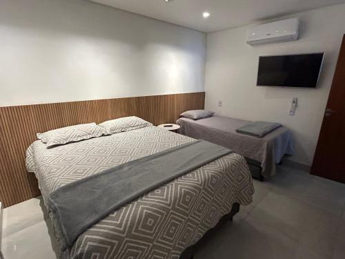 um quarto com duas camas e uma televisão na parede em Casa 600 Campina Grande em Campina Grande