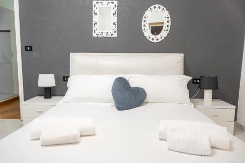 Una cama blanca con una almohada azul del corazón. en La Villa Del Senatore, en Gravina in Puglia