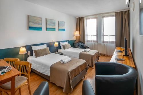 a hotel room with two beds and a couch at Corvin Hotel Budapest Residence in Budapest