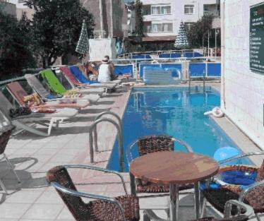 - une piscine avec des chaises, une table, une table et des chaises dans l'établissement Delta Hotel, à Didim