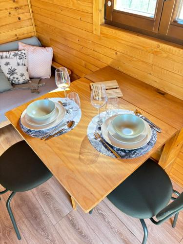 une table en bois avec des assiettes et des verres à vin dessus dans l'établissement Roulotte Achloma, à Fréjus