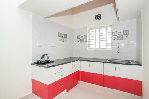 una cocina con armarios rojos y blancos y fregadero en Manyata Royal Mac, en Bangalore