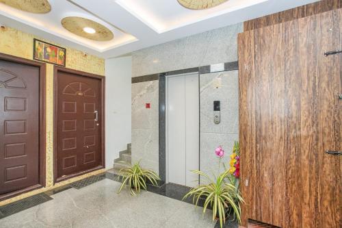 a lobby with two brown doors and plants at Manyata Royal Mac in Bangalore