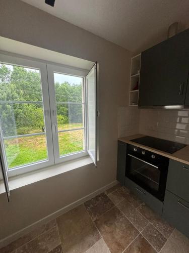 - une cuisine avec deux fenêtres et une cuisinière dans l'établissement Maison entre Terre et Mer, à Curzon