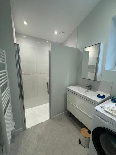 une salle de bain blanche avec une douche et un lavabo dans l'établissement Maison entre Terre et Mer, à Curzon