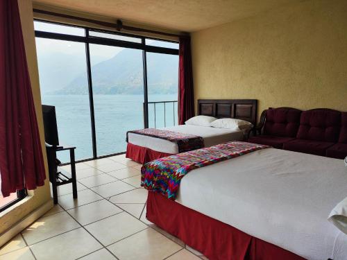 a hotel room with two beds and a large window at Hotel Restaurante La Villa de los Dioses in San Antonio Palopó