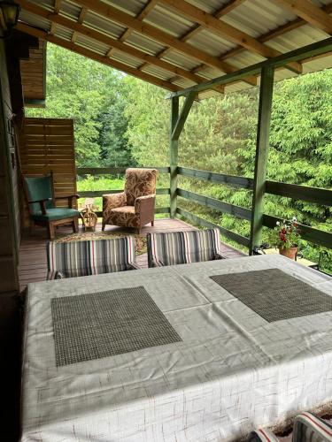 a porch with a bed and a chair on a deck at Agroturystyka u Basi i Waldka in Zelwa