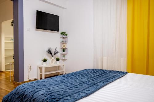 Un dormitorio con una cama y un televisor de pantalla plana. en Central Bucharest Retreat, en Bucarest