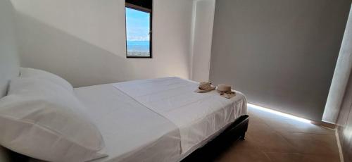 a bedroom with a white bed with a window at EM Somos AT HOME Lindo Apartamento con Aire Acondicionado in Neiva