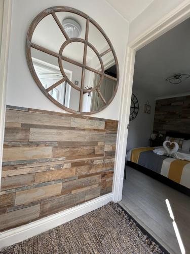 una camera da letto con parete in legno di recupero e specchio circolare di Dana guest suite a Horley