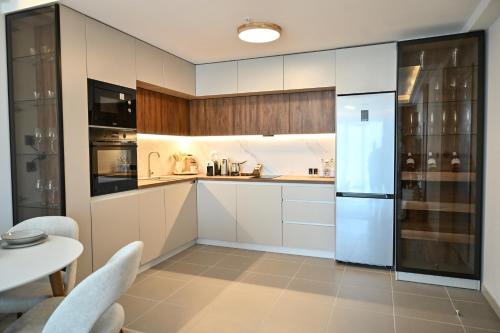 a kitchen with white cabinets and a white refrigerator at Portokali Sky Apartment in Skopje