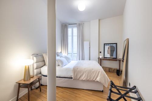 une chambre blanche avec un lit et une chaise dans l'établissement Luxury appartment near Louvre -TopQuartier- near metro, à Paris