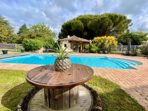une table en bois avec un ananas dessus à côté d'une piscine dans l'établissement Domaine du Galon d'Or, à Arvert