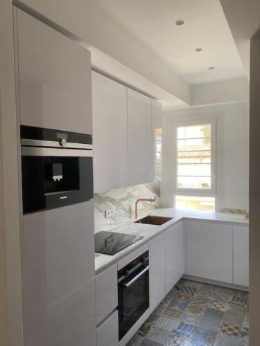 une cuisine blanche avec un évier et une cuisinière dans l'établissement Appart Saint Jean pieds dans l'eau, à Saint-Jean-Cap-Ferrat