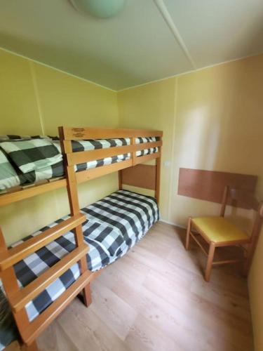- une chambre avec 2 lits superposés et une chaise dans l'établissement Mobile home des bois, à Rouffignac-Saint-Cernin-de-Reilhac