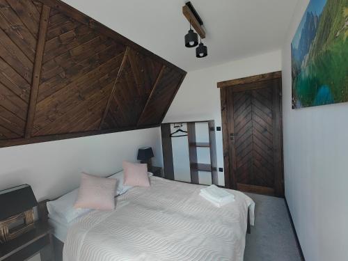 a bedroom with a white bed with pink pillows at Na polanie in Czerwienne
