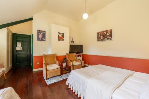 a bedroom with a bed and two chairs and a tv at Boutique Hotel Dobra Vila Bovec in Bovec