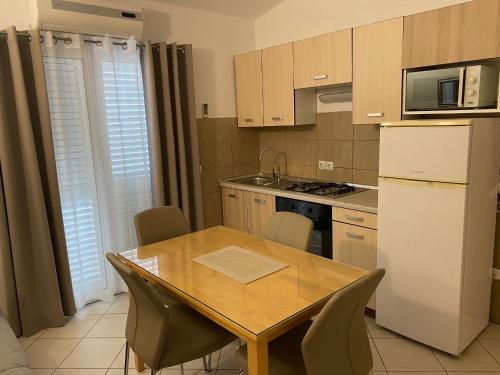 a kitchen with a table and a refrigerator and a table and chairs at Apartments Lolo in Privlaka