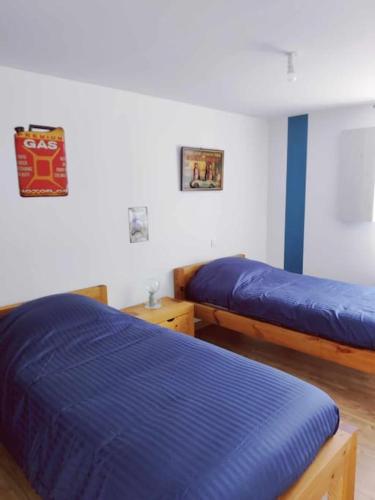 - une chambre avec 2 lits avec des draps bleus dans l'établissement Gîte des Prés, à La Noë-Blanche