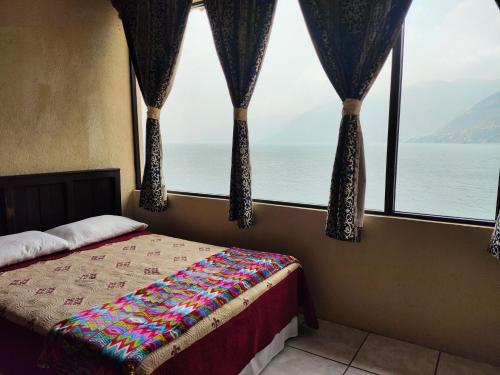 a bedroom with a bed with a view of the ocean at Hotel Restaurante La Villa de los Dioses in San Antonio Palopó