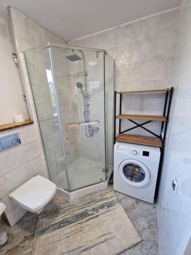 a bathroom with a shower and a washing machine at Little Wish in Gdańsk