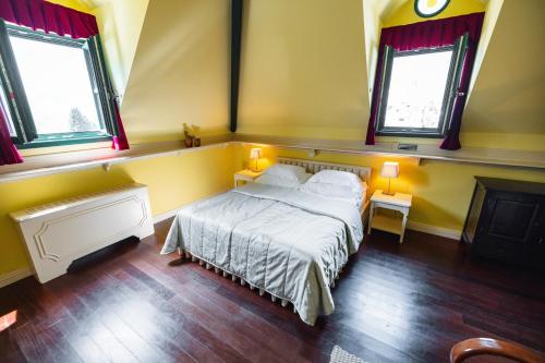 a bedroom with a bed and two windows at Boutique Hotel Dobra Vila Bovec in Bovec