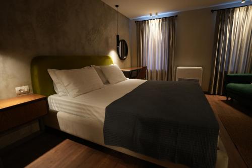 a bedroom with a large bed and a green chair at Castlefront Villa in Gjirokastër