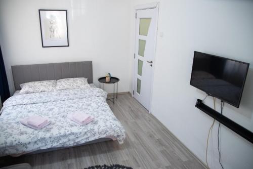 a bedroom with a bed and a flat screen tv at Nano Apartment in Prizren