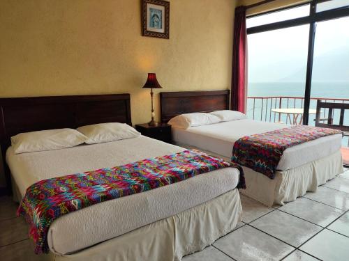 two beds in a room with a view of the ocean at Hotel Restaurante La Villa de los Dioses in San Antonio Palopó