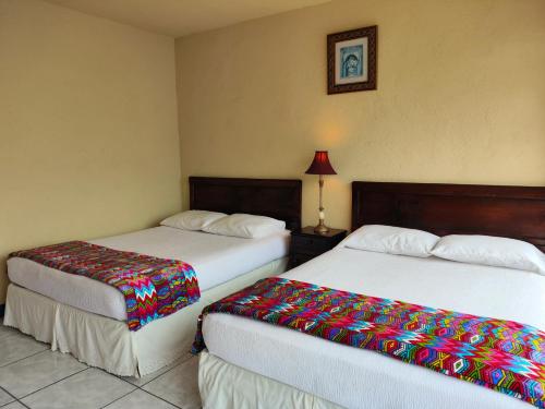 a hotel room with two beds with colorful blankets at Hotel Restaurante La Villa de los Dioses in San Antonio Palopó