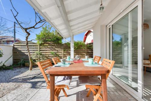 une table et des chaises en bois sur une terrasse dans l'établissement Maisonnette à deux pas de la plage, à Andernos-les-Bains