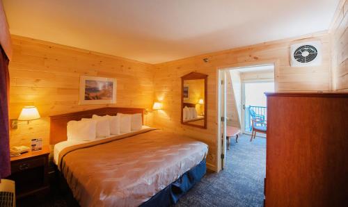 ein Schlafzimmer mit einem Bett in einem Holzzimmer in der Unterkunft Quality Inn & Suites Beachfront in Mackinaw City