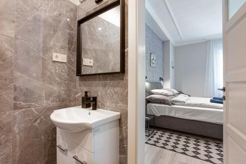 a bathroom with a sink and a mirror and a bed at Buda Castle Serpentine Apartments in Budapest