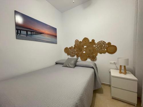 a bedroom with a bed and a picture on the wall at Vistas al mar a 10 metros de la Playa de Regla in Chipiona