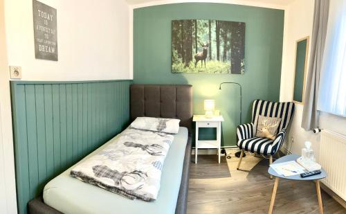 a small bedroom with a bed and a chair at Pension Trautheim - Am Stadtpark in Bad Harzburg