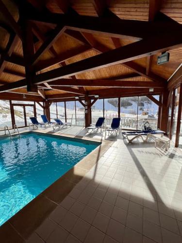 une grande piscine avec des chaises dans un bâtiment dans l'établissement Studio au pied des pistes avec vue sur la vallée, à Ustou