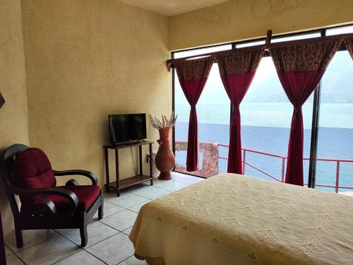 a bedroom with a bed and a tv and a window at Hotel Restaurante La Villa de los Dioses in San Antonio Palopó