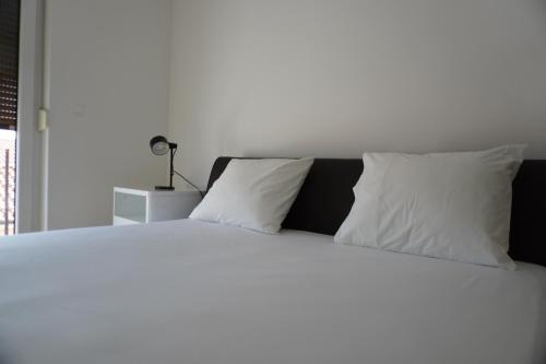 a white bed with white pillows and a lamp at Casa Capodistria with sea view in Koper