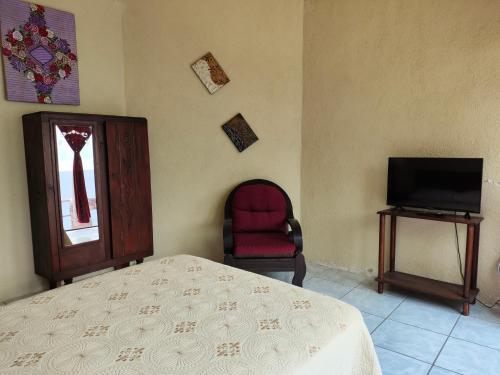 a bedroom with a bed and a chair and a television at Hotel Restaurante La Villa de los Dioses in San Antonio Palopó